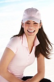 Portrait of happy woman with brown hair wearing pink polo t-shirt and cap, laughing