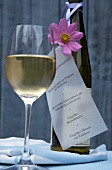 Close-up of wine glass, bottle and menu with flower