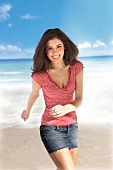 Portrait of happy woman in red and white striped t-shirt walking on the beach, smiling