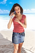 Woman on beach looking in water bottle
