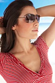 Woman with dark hair wearing red and white striped t-shirt and sunglasses, looking away