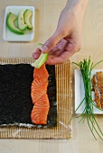 Salmon being placed on nori sheet for preparation of sushi, step 3