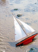 Close-up of toy sail boat in sand