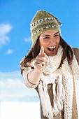 Portrait of pretty woman in beige coloured scarf and green knit cap gesturing, smiling