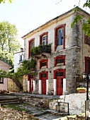 Wein wächst an Hausfassade, rote Tü- ren, Griechenland