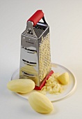 Grater and peeled raw potatoes on plate