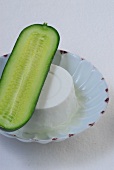 Half cucumber and yogurt on bowl