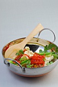 Raw vegetables with wooden spoon in wok