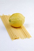 Raw spaghetti and whole lemon on white background