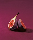 One halved fresh fig on red background