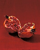 One halved pomegranate seeds on red background