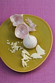 Pieces, strips, slices and whole garlic bulb on plate