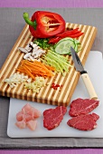 Vegetables sliced in thin strips and fillet of raw meat on cutting board