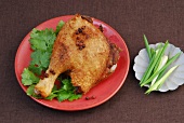 Fried duck garnished with szechwan pepper and coriander leaves on plate