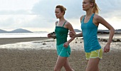 Two women in sportswear jogging on beach