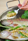 Vegetables being added on trout in steamer while preparing steamed salmon trout, step 2