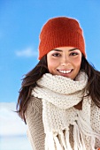 Portrait of happy young woman wearing red knitted hat and scarf smiling