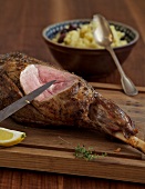 Cooked lamb being sliced on board