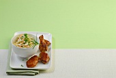 Bowl of cabbage salad with chicken wings on plate