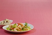 Shrimp with cucumber sauce on plate with bowl of wild rice