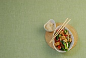 Stir-fried vegetables in bowl with chopsticks, overhead view