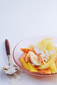 Fruit salad with lemongrass syrup and coconut chips in glass bowl
