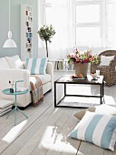 Living room in pastel shades, white couch and vase of flowers on coffee table