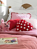 Cot with red and white checked polka dot bedding and pillows