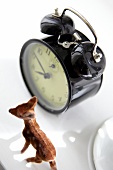 Black alarm clock with animal figurine on white background