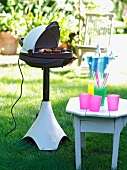 Electric grill and stool with plastic cups in garden