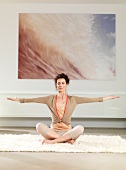 Woman sitting cross-legged with her hands raised meditating peacefully