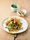 Spaghetti with vegetables, chicken, cherry tomatoes and sugar snap peas on plate
