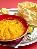 Close-up of lentil with ginger and pumpkin in bowl and pappadums on plate