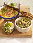 Prawns with scrambled eggs, herring salad and whole grain bread with leeks in bowls