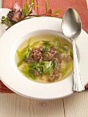 Clear oxtail soup with leeks in serving dish