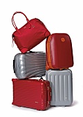Stack of various red and silver travel bags against white background