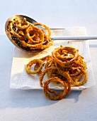 Fried crispy onion rings with poppy on paper and frying spoon, Indian fast food 