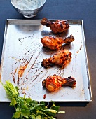 Tandoori chicken drums on baking dish with coriander dip in bowl, Indian fast food
