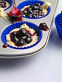 Blueberry with dough in paper case for preparing muffin, step 1