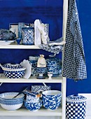 Blue-and-white country house-style crockery on a wooden shelf against a blue-painted wall