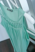 Close-up of mint green top with decorative cut-out on hanger