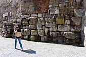Woman walking across stone wall at St George's square in Regensburg, Bavaria, Germany