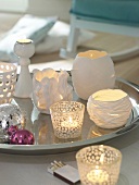 Lit candles in lanterns made of porcelain and glass on silver tray