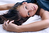 Portrait of sensual gray eyed woman with dark hair relaxing on bed