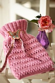 Close-up of pink knitted hot water bottle cover with artificial butterfly on it