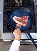 Steak in frying pan, elevated view