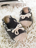 Close-up of black and white woollen slippers on white fur carpet
