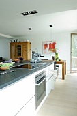 White kitchen cabinets with oven in dining area with white walls