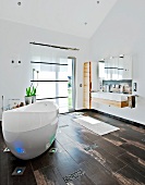 Badezimmer mit freistehender ovaler Wanne und Holzdielenboden