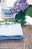 Close-up of light blue table linen with stack of dishes and hydrangeas